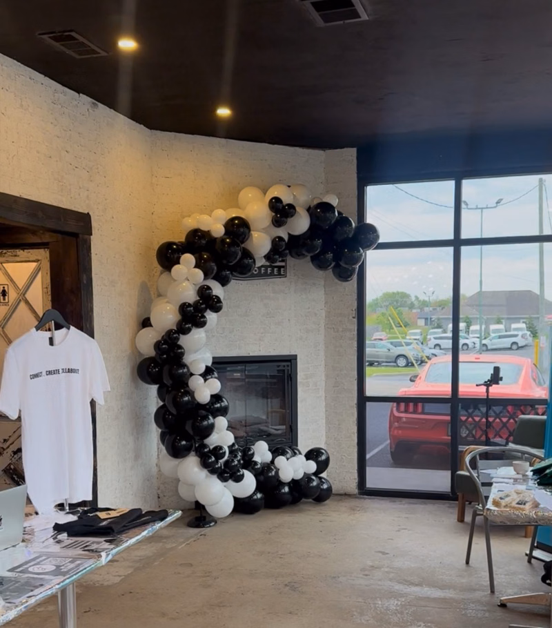 Black and white organic balloon garland curving around a fireplace in a coffee shop